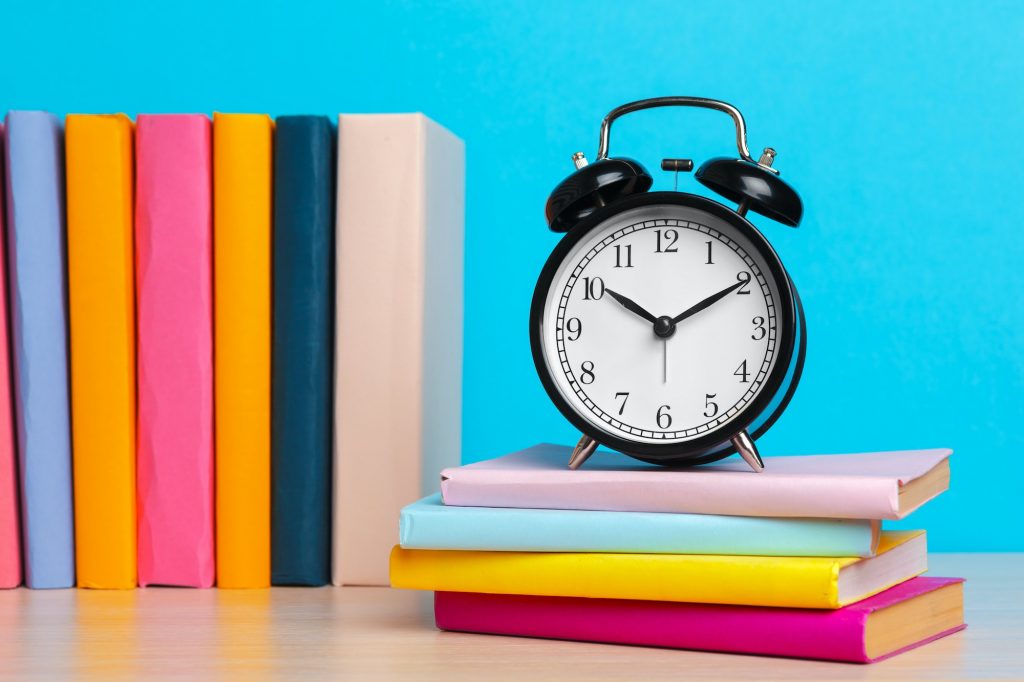 Back to school background with books and alarm clock